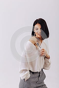 Attractive young business girl with makeup brushes posing on plain background. concept of makeup and cosmetics
