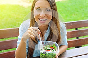 Attractive young business woman have a lunch sitting in city park looking at camera.