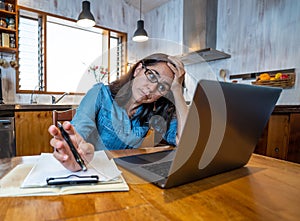 Attractive young business woman working from home on her computer stressed, tired and overwhelmed