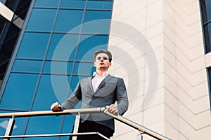 Attractive young businessman in front of a modern office building on a beautiful sunny day.