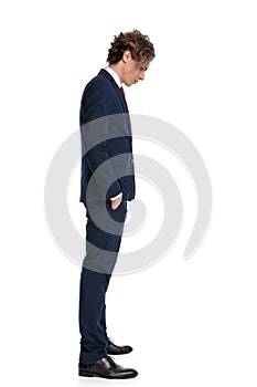 Attractive young businessman with hands in pockets looking down