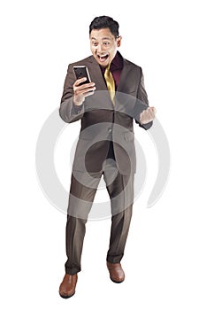 Attractive young businessman receive good news on his phone, happy winning gesture