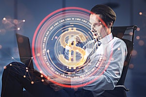 Attractive young businessman sitting and using laptop with abstract red digital dollar coin with polygonal bokeh mesh on blurry
