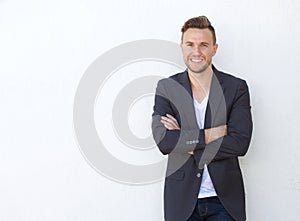 Attractive young businessman smiling against white wall