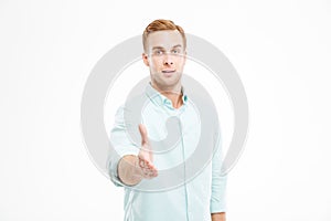 Attractive young businessman standing and giving his hand for handshake