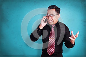 Attractive young businessman talking on his phone, shocked crying