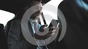 Attractive young businessman using cellphone for remote communication while having rest in the car. People and social