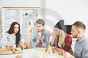 Attractive young businesspeople eating at workplace