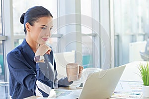 Attractive young businesswoman is enjoying hot tea