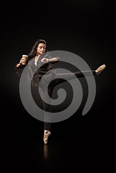 attractive young businesswoman in formal wear and ballet shoes with coffee to go checking time on black