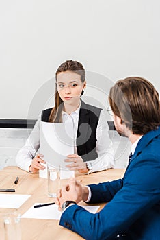 attractive young businesswoman listening to colleague while holding documents