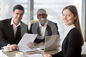 Attractive young businesswoman looking at camera, female team le