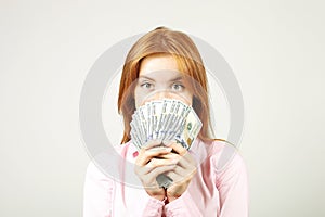 Attractive young businesswoman posing with bunch of USD cash in hands showing positive emotions and happy facial expression.