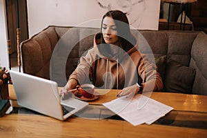 Attractive young businesswoman is typing on laptop computer and working with paper document.
