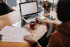 Attractive young businesswoman is typing on laptop computer and working with paper document.