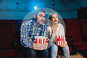 Attractive young caucasian couple watching a film at a movie theater