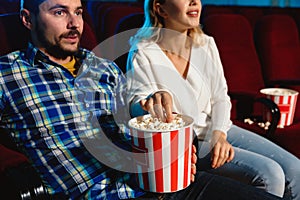 Attractive young caucasian couple watching a film at a movie theater