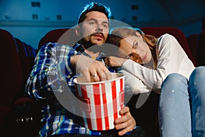 Attractive young caucasian couple watching a film at a movie theater