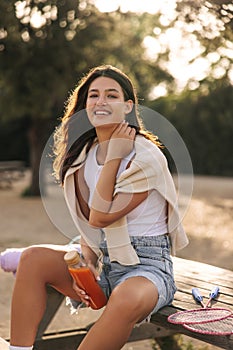 Attractive young caucasian woman smiling, posing looking at camera sitting on table in nature.