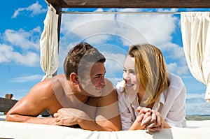 Attractive young couple on chill out bed under blue summer sky