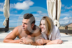 Attractive young couple on chill out bed under blue summer sky