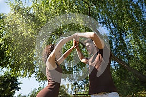 Attractive young couple dancing sensual bachata with arms up in an outdoor park surrounded by greenery. Latin dance concept,