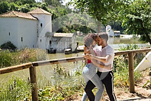 Attractive young couple dancing sensual bachata in an outdoor park with a river in the background. Latin, sensual, folkloric,