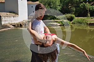 Attractive young couple dancing sensual bachata on a stone floor, in an outdoor park, next to a river. Latin dance concept,