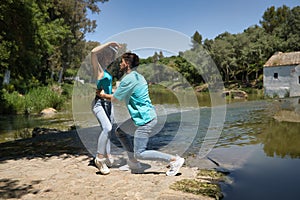 Attractive young couple dancing sensual bachata on a stone floor, in an outdoor park, next to a river. Latin dance concept,