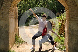 Attractive young couple dancing sensual bachata under an ancient stone arch in an outdoor park. Latin, sensual, folkloric, urban