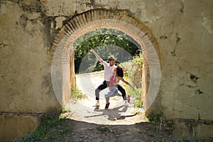 Attractive young couple dancing sensual bachata under an ancient stone arch in an outdoor park. Latin, sensual, folkloric, urban