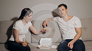 Attractive young couple having a night in at home and enjoying eating japanese take away food