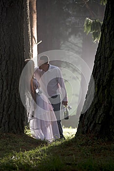 Attractive young couple leaning against tree trunk in misty forest