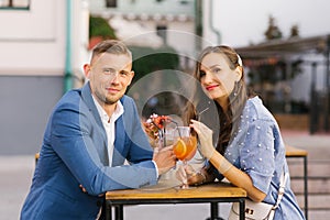 Attractive young couple in love sitting at the cafe table outdoors