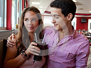 Attractive Young Couple Sharing Soda at Restaurant