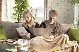 Attractive young couple using devices together, tablet, laptop, smartphone, headphones wireless. Gadgets and
