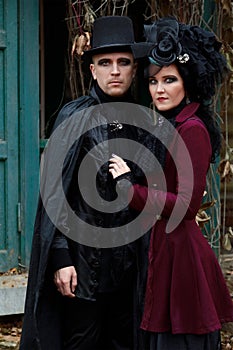 Attractive young couple wearing old-fashioned vampire-style clothes outdoors