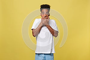 Attractive young dark-skinned male having stunned and schocked look with hand closing mouth.