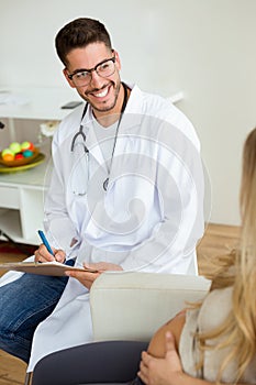 Attractive young doctor giving a routine check to beautiful pregnanat woman in medical office.