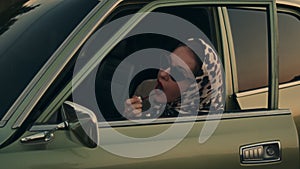 Attractive young elegant woman puts a lipstick in her retro car.