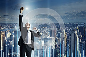 Attractive young european businessman reaching for highest point of abstract business chart on city background with mock up place