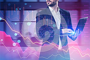 Attractive young european businessman using laptop with pink crisis business and forex chart on blurry office interior background