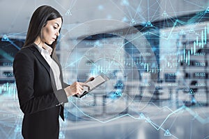 Attractive young european businesswoman using tablet with abstract glowing forex chart, map and arrows on index hologram, blurry