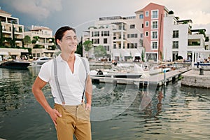 Attractive young fashion man in a suit against the background of porto montenegro