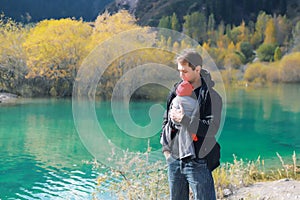 Attractive young father with her infant baby in sling outdoor. Babywearing concept