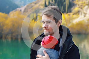 Attractive young father with her infant baby in sling outdoor. Babywearing concept