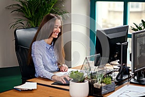 Attractive young female architect in blue shirt working in the modern office.