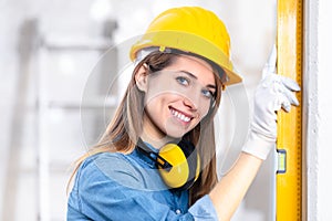 Attractive young female builder checking level