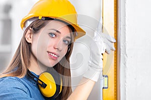 Attractive young female builder checking level