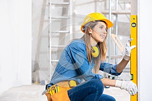 Attractive young female builder checking level